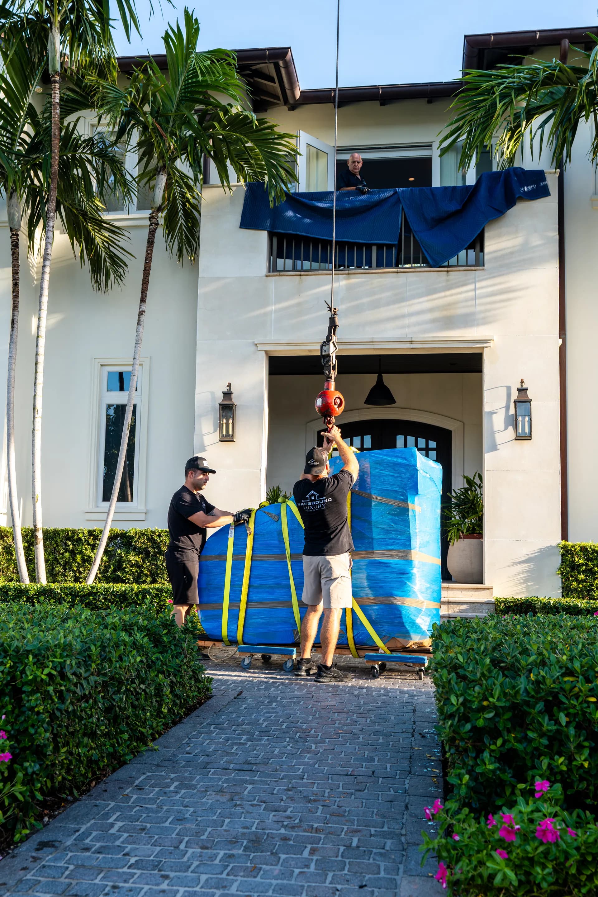 Safebound Luxury crew hoisting a large wrapped asset into a Palm Beach estate